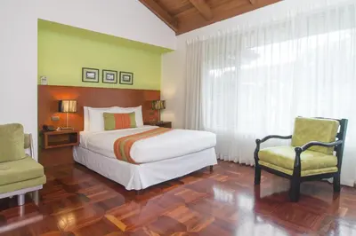 a bedroom with a large bed and two chairs at Terrazas de Golf Boutique Hotel in San José