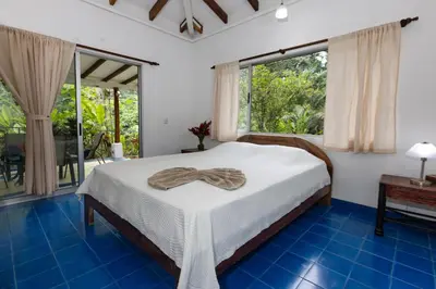 a bedroom with a bed and a large window at Casa Cedro - Portasol Vacation Rentals in Matapalo