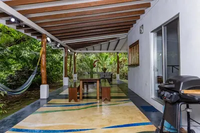 an outdoor patio with a table and chairs and a grill at Casa Cedro - Portasol Vacation Rentals in Matapalo