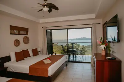 a bedroom with a bed and a balcony with a view at Eco Boutique Hotel Vista Las Islas Reserva Natural in Paquera