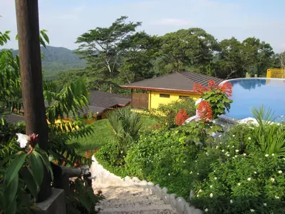 a garden with a yellow house and a swimming pool at Eco Boutique Hotel Vista Las Islas Reserva Natural in Paquera