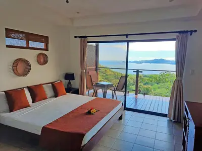 a bedroom with a bed and a balcony with a view at Eco Boutique Hotel Vista Las Islas Reserva Natural in Paquera