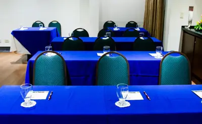 a row of blue tables and chairs with wine glasses at Rincon del Valle Hotel & Suites in San José