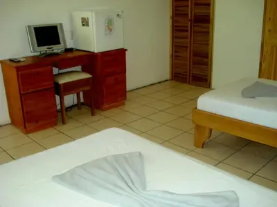 a bedroom with two beds and a desk with a computer at Mapi's Cabins in Paquera