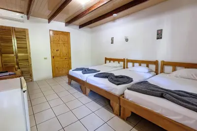 two beds in a room with a kitchen at Mapi's Cabins in Paquera