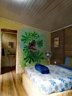 a bedroom with a bed with a painting on the wall at Cecropia Ecolodge in Fortuna