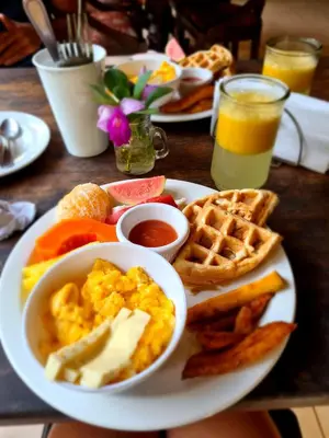 a plate of breakfast food with eggs and waffles and toast at Cecropia Ecolodge in Fortuna
