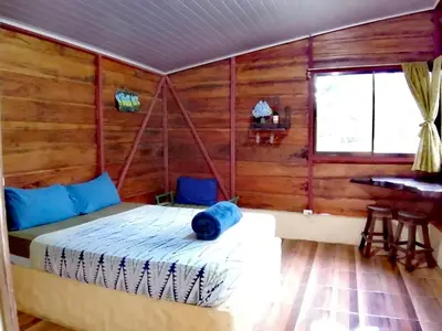 a bedroom with a bed in a room with wooden walls at Cecropia Ecolodge in Fortuna