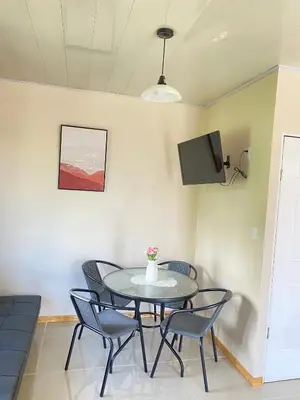a dining room with a table and chairs and a tv at Agutí Apartment in Manuel Antonio