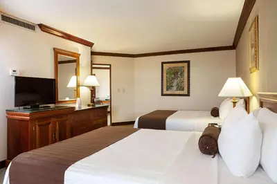a hotel room with two beds and a flat screen tv at Wyndham San Jose Herradura in San José
