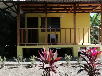 a yellow house with a balcony and some plants at Chill-Inn Nosara in Nosara