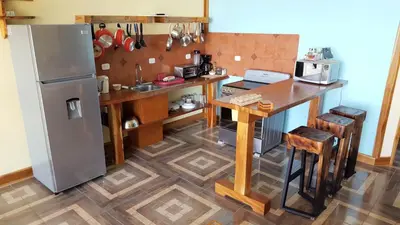 a kitchen with a refrigerator and a wooden table at Above the Gulf, Vacation House in Monteverde Costa Rica