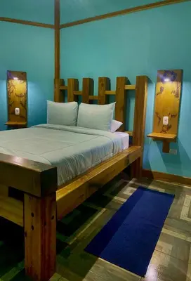 a bedroom with a wooden bed with a blue wall at Above the Gulf, Vacation House in Monteverde Costa Rica
