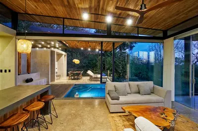 a living room with a couch and a table and a pool at SELVA RESORT Ocean View Luxury Villas in Santa Teresa Beach