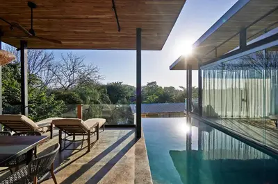 an outdoor pool with chairs and a table next to a house at SELVA RESORT Ocean View Luxury Villas in Santa Teresa Beach