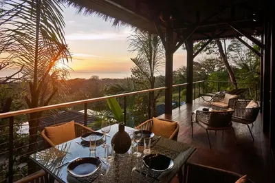 a dining room with a table and chairs on a balcony at SELVA RESORT Ocean View Luxury Villas in Santa Teresa Beach