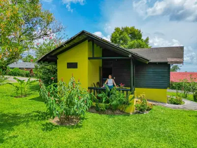 a woman standing in the doorway of a yellow house at Hotel Campo Verde in Fortuna