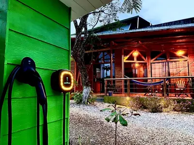 a green building with a black bird on the side of it at Hoja Azul in Hojancha