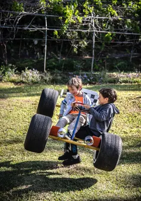 two children riding on a toy car with large wheels at Natural Wonders House in Monteverde Costa Rica