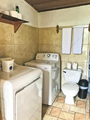 a small bathroom with a toilet and a washing machine at Natural Wonders House in Monteverde Costa Rica