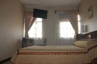 a bedroom with a bed and two windows at Hotel Santa Maria Inn in Alajuela City