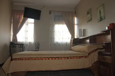 a bedroom with a bed and two windows at Hotel Santa Maria Inn in Alajuela City