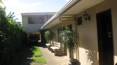 a patio with chairs and a palm tree next to a building at Hotel Santa Maria Inn in Alajuela City