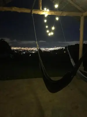 a hammock hanging from a tent at night with a city at Cabaña Mountain View in Heredia