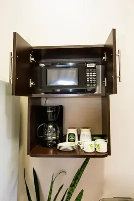 a microwave oven hanging on a wall with cups on a shelf at Apartamento Lantana ,Monteverde con Aire Acondicionado y Lavanderia in Monteverde Costa Rica