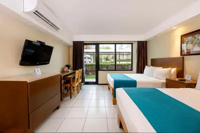 a hotel room with two beds and a flat screen tv at Best Western Jaco Beach All Inclusive Resort in Jacó