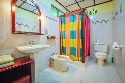 a bathroom with a rainbow shower curtain and a toilet at Lands in Love Hotel and Resort in Colonia Palmareña