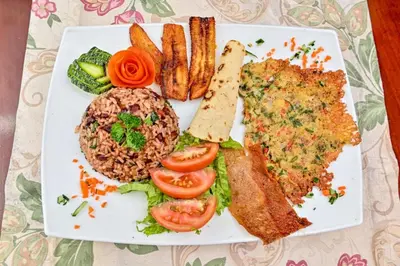 a plate of food with fish and rice and french fries at Lands in Love Hotel and Resort in Colonia Palmareña