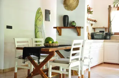 a kitchen with a wooden table and white chairs at Pazifico Villas in Playa Avellana