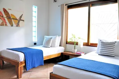 two beds in a room with a window at Pazifico Villas in Playa Avellana