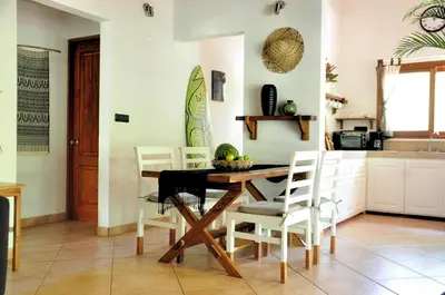 a kitchen with a table with chairs and a surfboard at Pazifico Villas in Playa Avellana