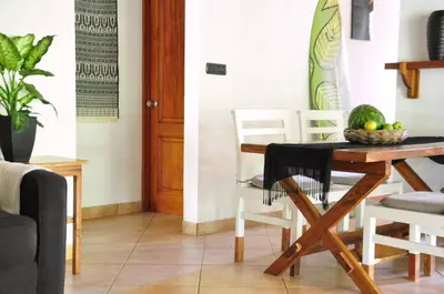a dining room with a wooden table and white chairs at Pazifico Villas in Playa Avellana