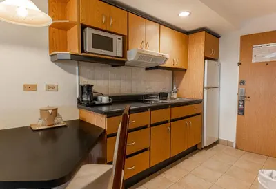 a kitchen with wooden cabinets and a microwave at Irazú Hotel & Studios in San José