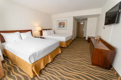 a hotel room with two beds and a flat screen tv at Irazú Hotel & Studios in San José
