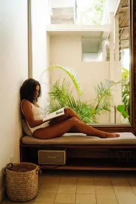 a woman sitting on a bed reading a book at Casa Keshet in Santa Teresa Beach