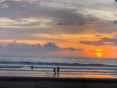 a group of people standing on the beach at sunset at 12B Jaco Sol Quadplex in Jacó