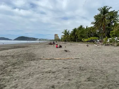 a group of people sitting on a sandy beach at 12B Jaco Sol Quadplex in Jacó