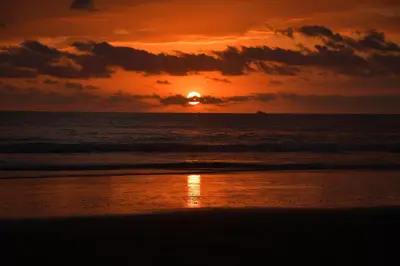 a sunset on the beach with a boat in the ocean at 12B Jaco Sol Quadplex in Jacó
