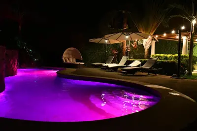 a pool with purple lighting in a backyard at night at Jaco Sol Quadplex 11A in Jacó