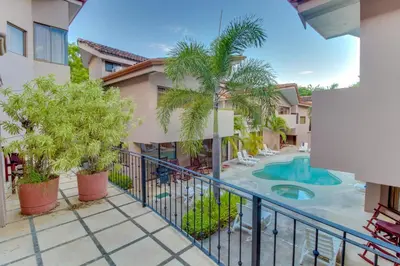 an apartment balcony with a pool and palm trees at The Cove at Playa Ocotal, units 5,6,7 and 8 in Coco