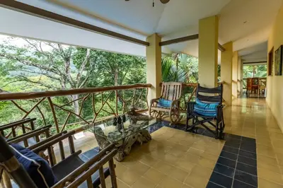 a porch with rocking chairs and a view of the forest at Casa Monos Locos - Portasol Vacation Rentals in Portalón