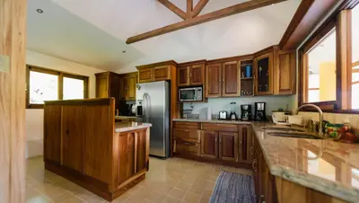 a kitchen with wooden cabinets and a stainless steel refrigerator at Casa Monos Locos - Portasol Vacation Rentals in Portalón