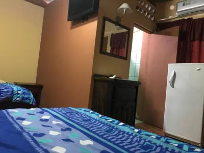 a bedroom with a bed and a refrigerator in it at Cabinas Yolymar in Puntarenas