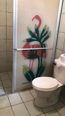 a bathroom with a toilet and a painting of a chicken at Cabinas Yolymar in Puntarenas