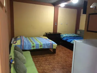 a bedroom with two beds and a tv in it at Cabinas Yolymar in Puntarenas