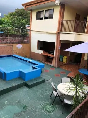 a pool in the backyard of a house with a table and chairs at Cabinas Yolymar in Puntarenas